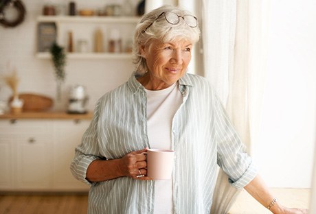 Senior woman looking out window while drinking tea
