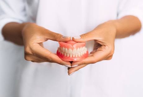 A dentist holding a pair of dentures