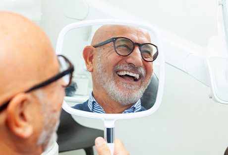 Man with black glasses smiling in reflection in mirror