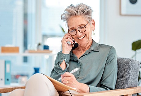 Woman with black glasses smiling while talking on phone