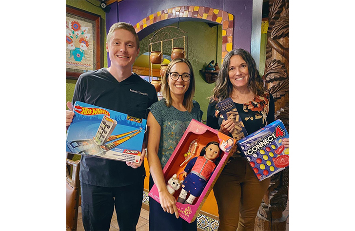 Dental team members holding donated gifts