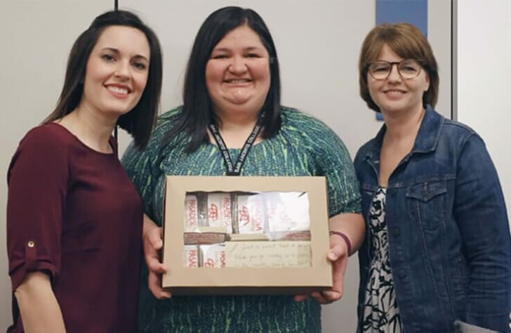 Dentistry team members with dental patient holding a prize