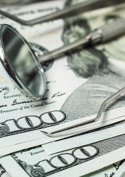 Dental tools lying on a stack of dollar bills