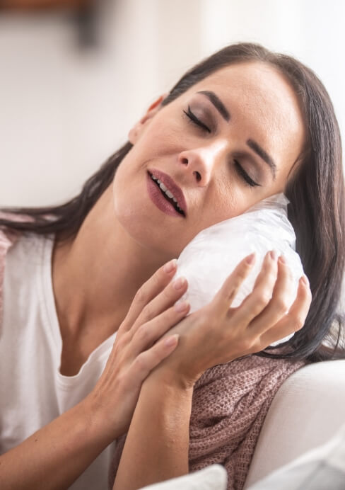 Woman holding ice to cheek after tooth extraction