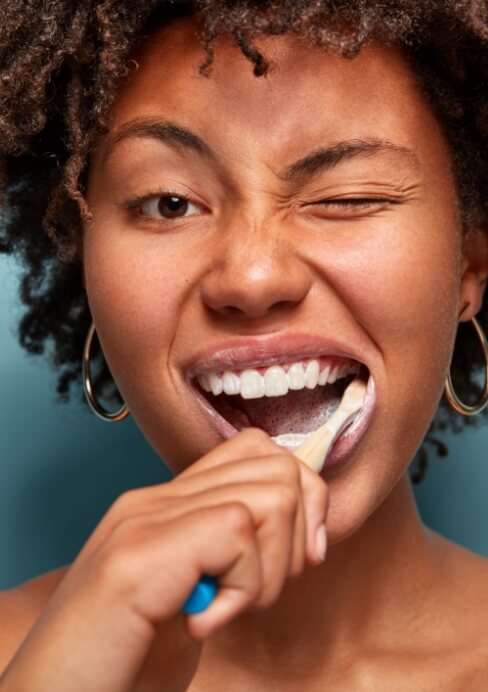 Woman brushing teeth to care for tooth colored fillings