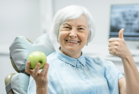 Woman smiling after receiving a dental implant restoration
