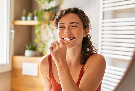Woman smiling while brushing her teeth
