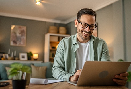 Man smiling while working on laptop at home