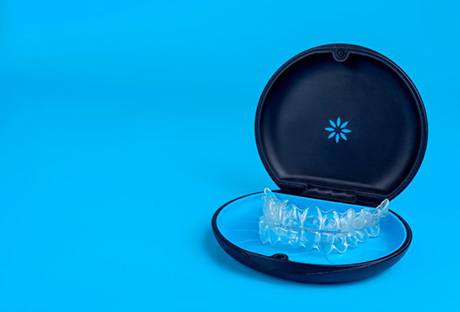 Invisalign trays sitting inside their case on blue background