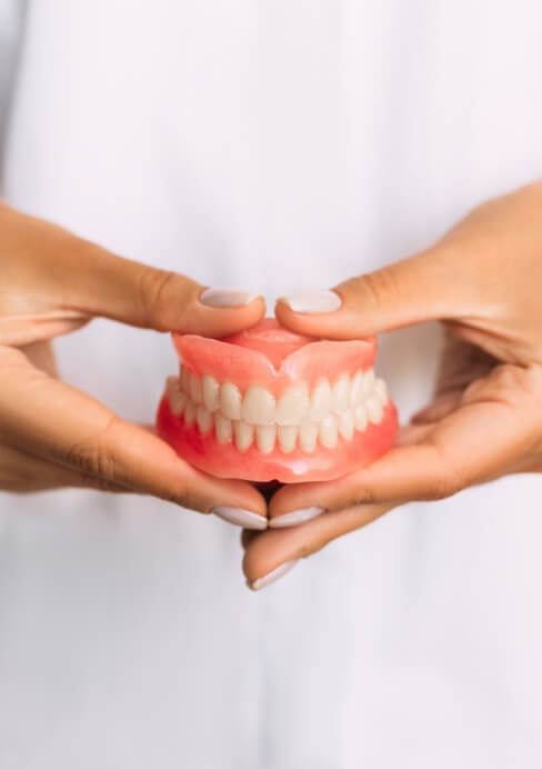 Dentist holding model smile used to explain tooth colored fillings