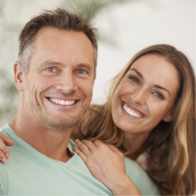 Man and woman smiling after emergency dentistry visit