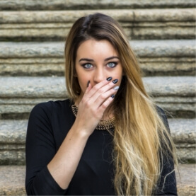 Woman covering her smile before gum disease treatment