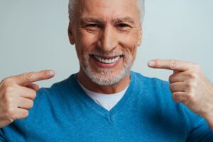 Senior man smiling and showing off dentures. 